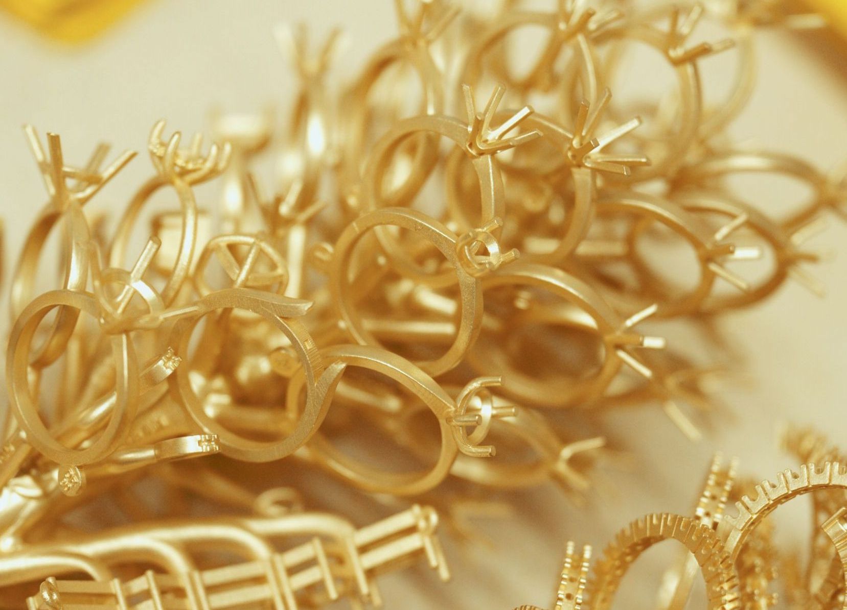 A horizontal, eye-level shot of a smiling woman with long brown hair talking on a black office phone. She is wearing a blue and black patterned shirt and a gold watch.