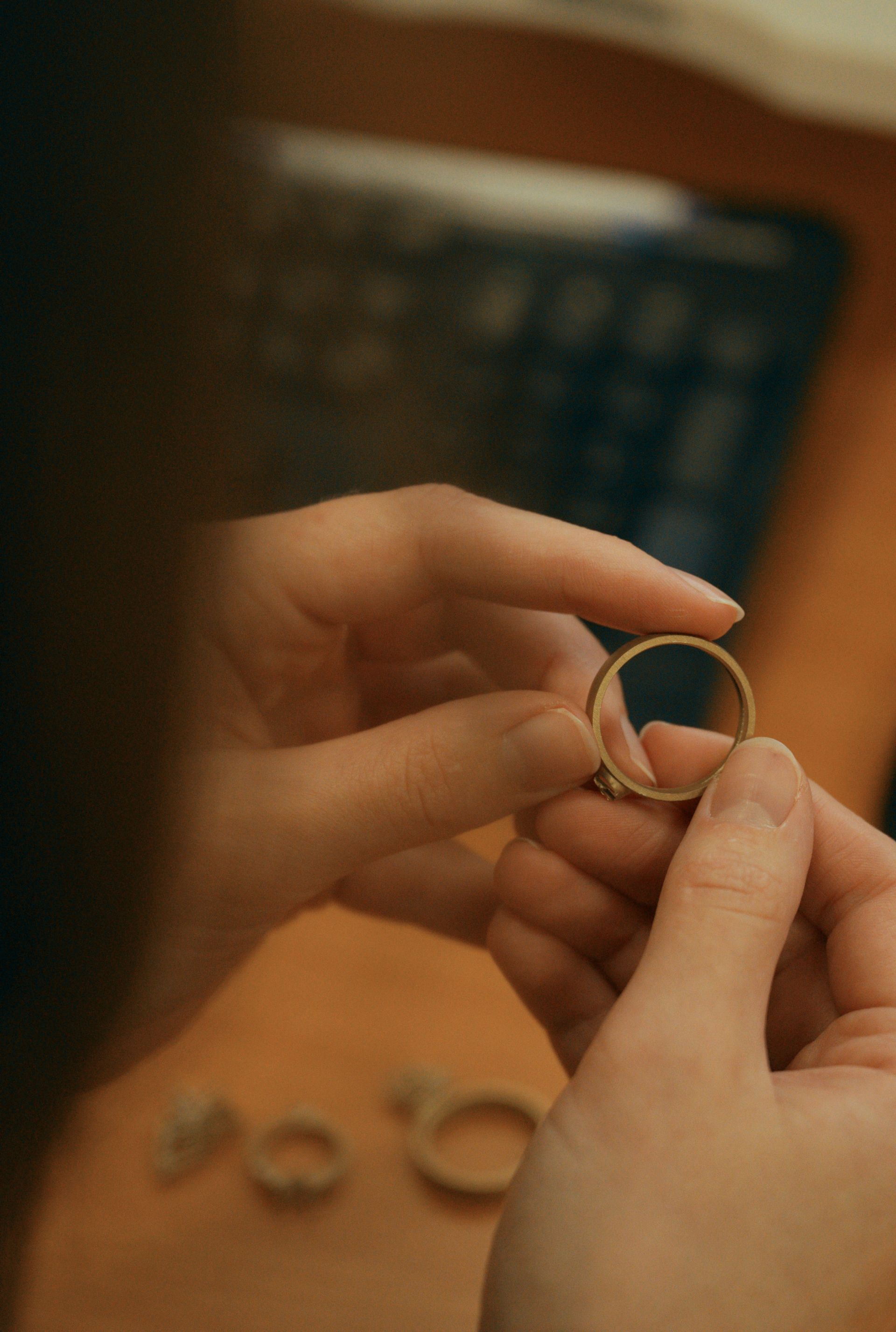 Close-up of a jeweler's hands meticulously examining a handcrafted gold ring.