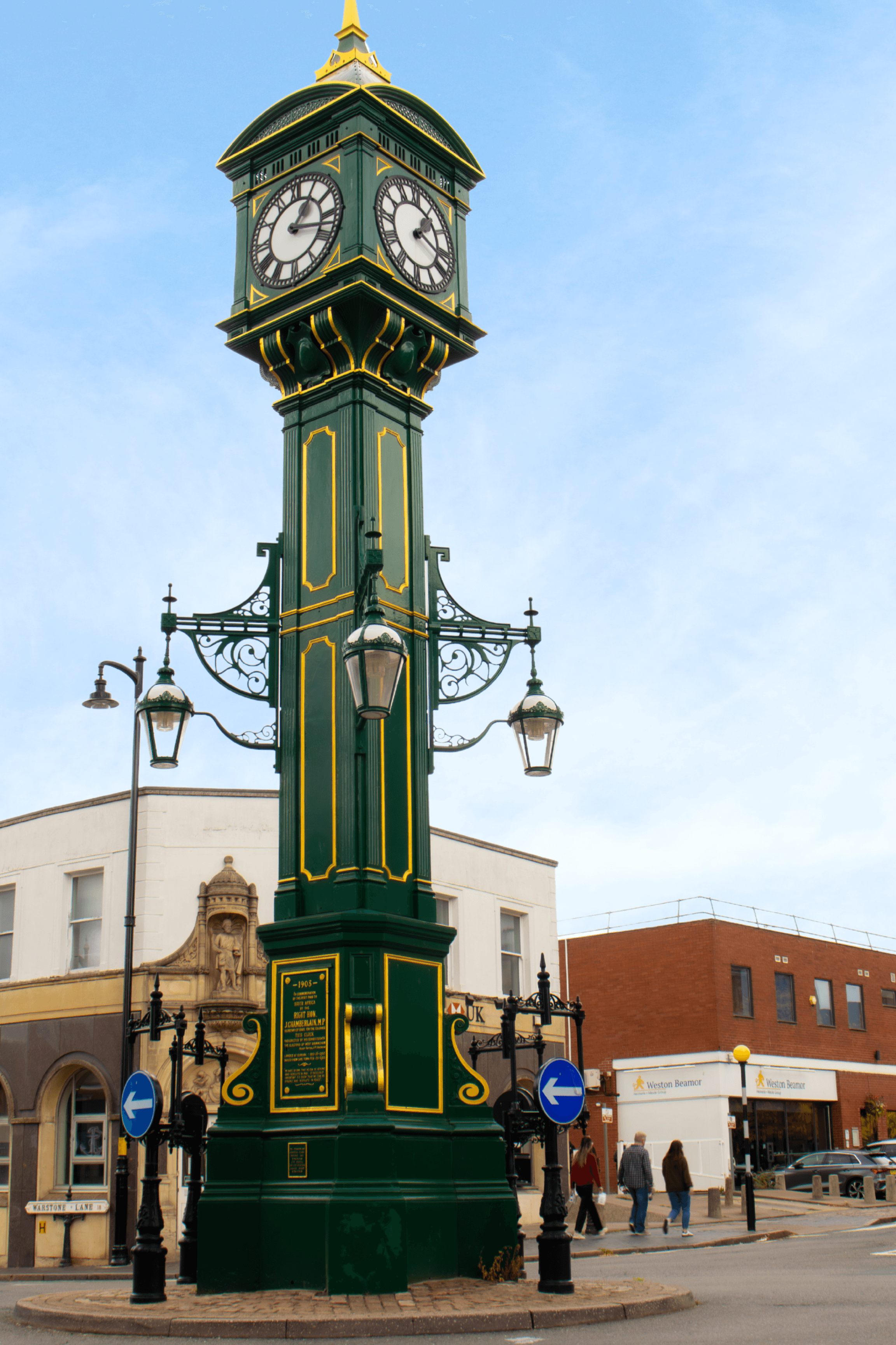 A low-angle shot of a historic green and gold clock tower in Birmingham's Jewellery Quarter.
