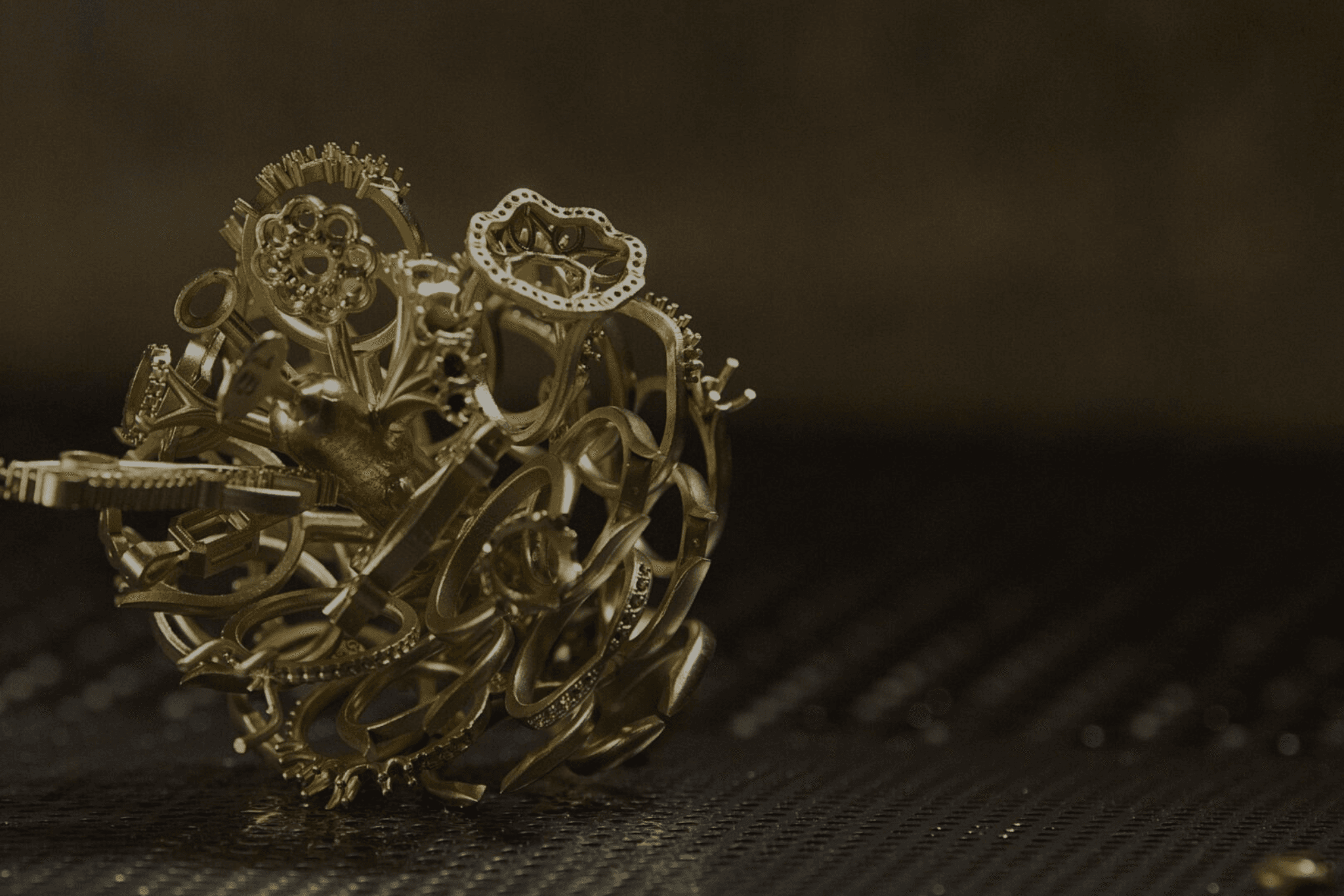 A chaotic bundle of metallic gears and cogs rests on a ribbed surface in dim light, conveying a sense of complexity and mechanical intricacy.
