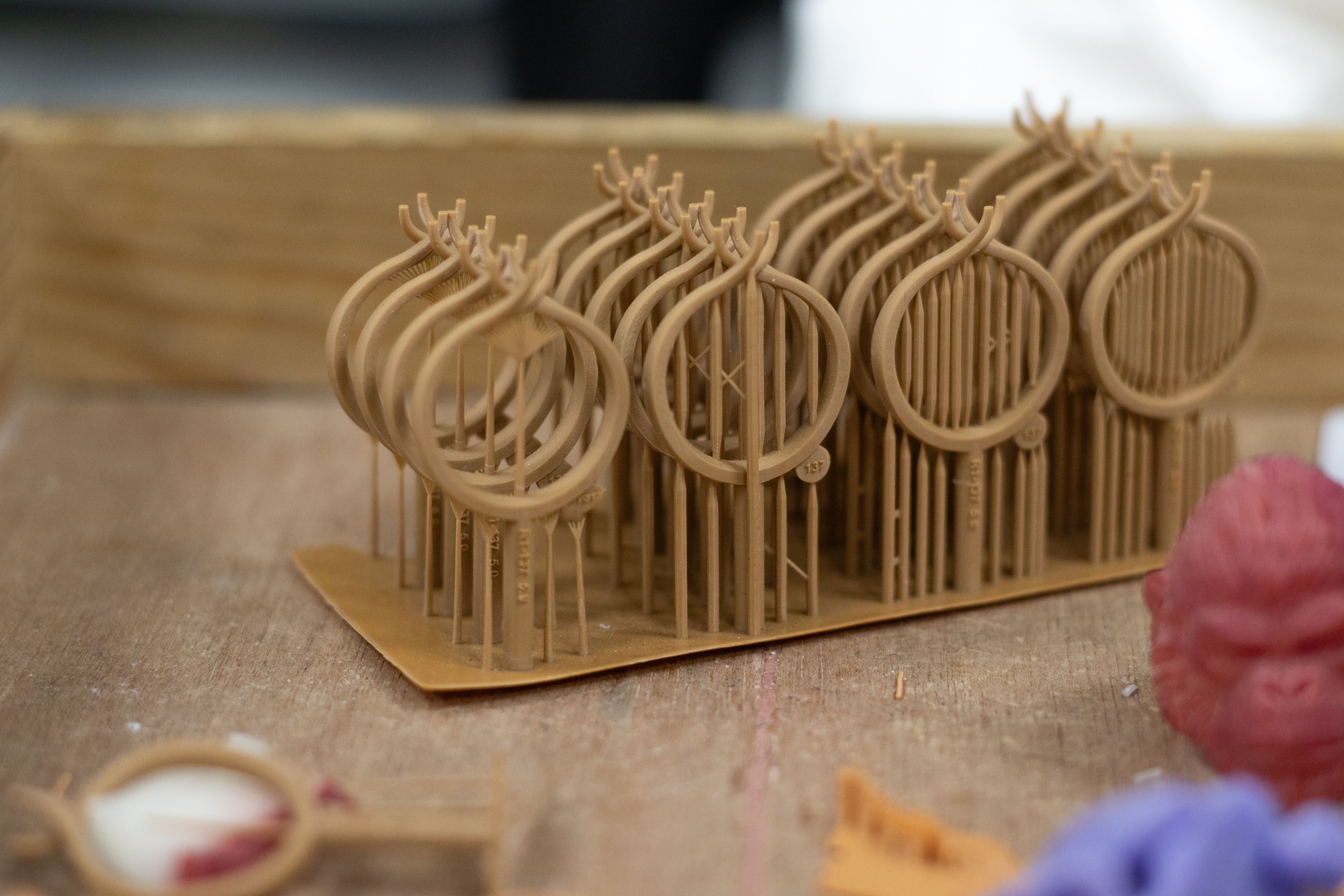A close-up, eye-level shot shows a series of 3D-printed or cast objects standing upright on a flat base.